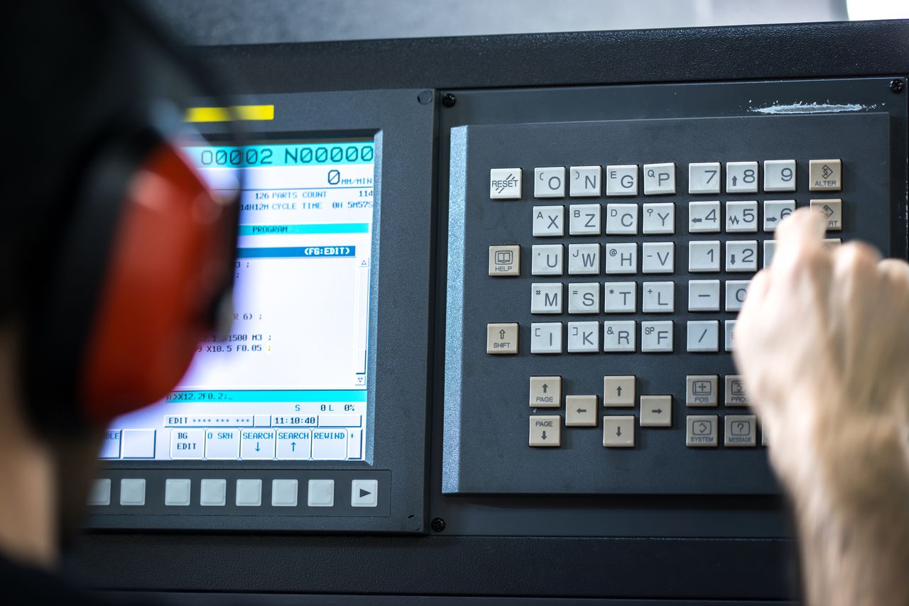 czlowiek ustawia parametry na panelu obrabiarki cnc