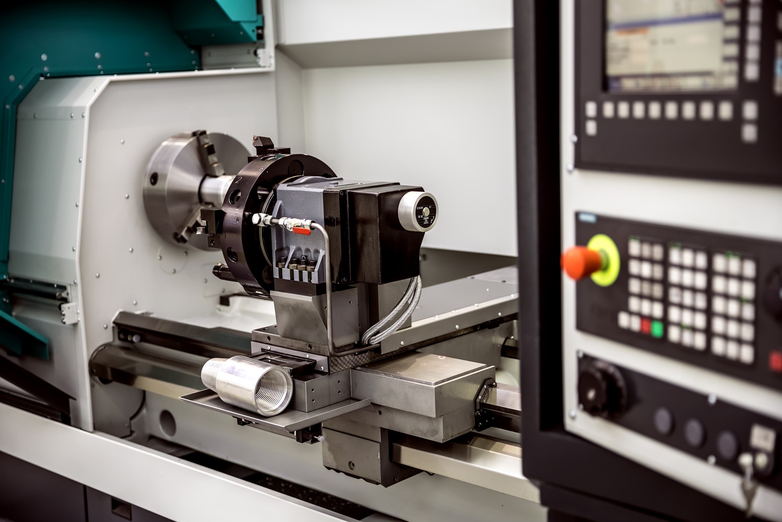 Zbliżenie na wnętrze tokarki CNC, ilustrujące proces toczenia metalu jako jeden z rodzajów obróbki CNC.