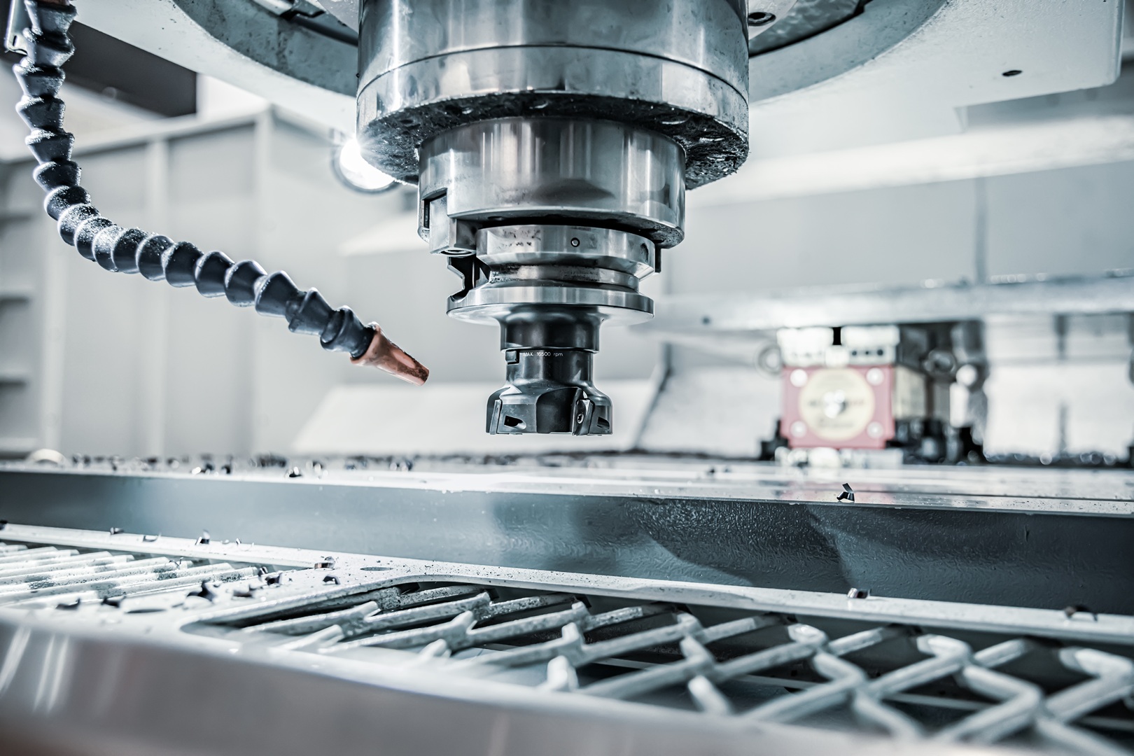 Zbliżenie na wrzeciono frezarki CNC z dyszą chłodziwa skierowaną na stół roboczy.